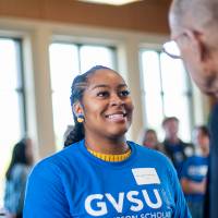 A student who received a Thompson Scholarship is shaking hands with Robert Thompson. Ellen Thompson is in the background.